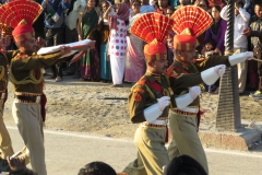 Uniformed guards carrying flag at Wagah Border crossing